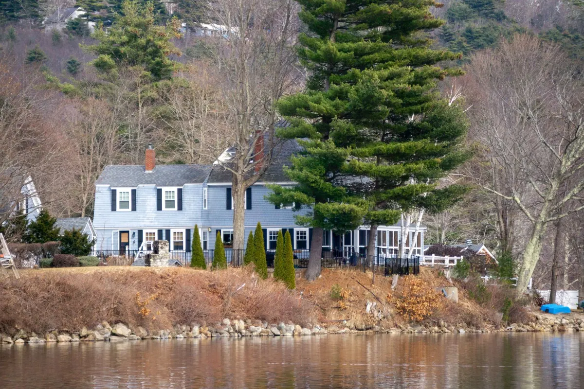 White clapboard house among pines above a pond in late autumn